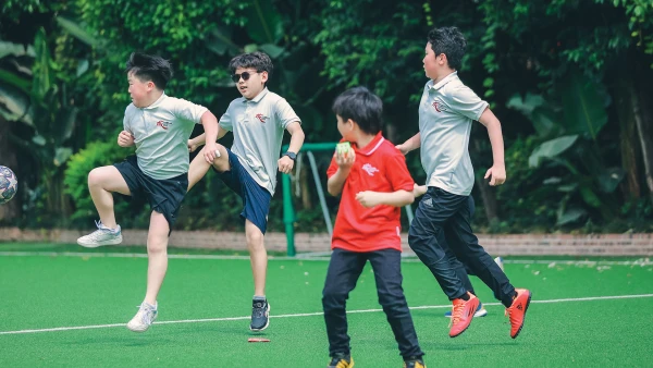 four boys playing soccer outside chengdu international school