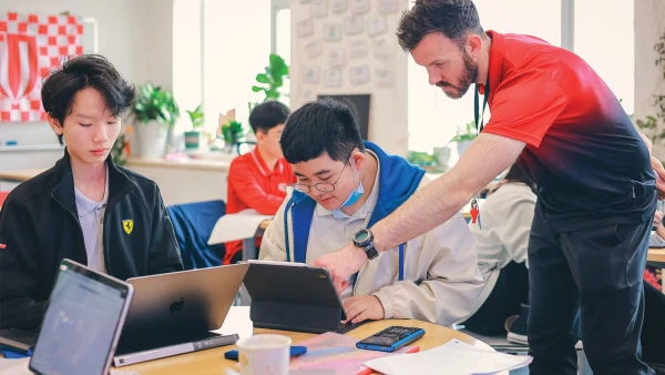 teacher helping students on computers about chengdu international school