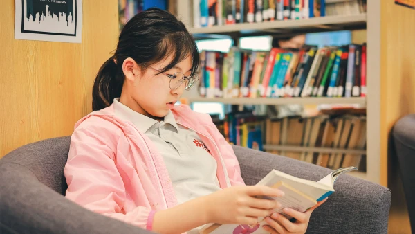 female student reading a book inside chengdu international school elementary library