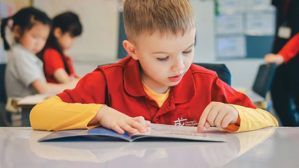 young male student reading a book at chengdu international school early childhood center