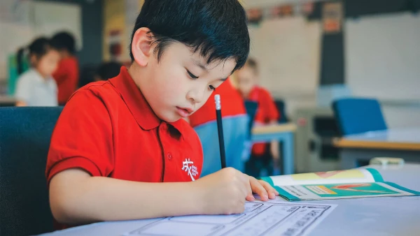 young male student writing homework at chengdu international school early childhood center