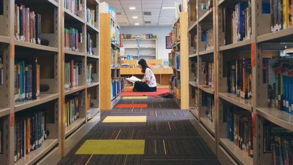 female teacher sitting on the floor reading inside chengdu international school high school library