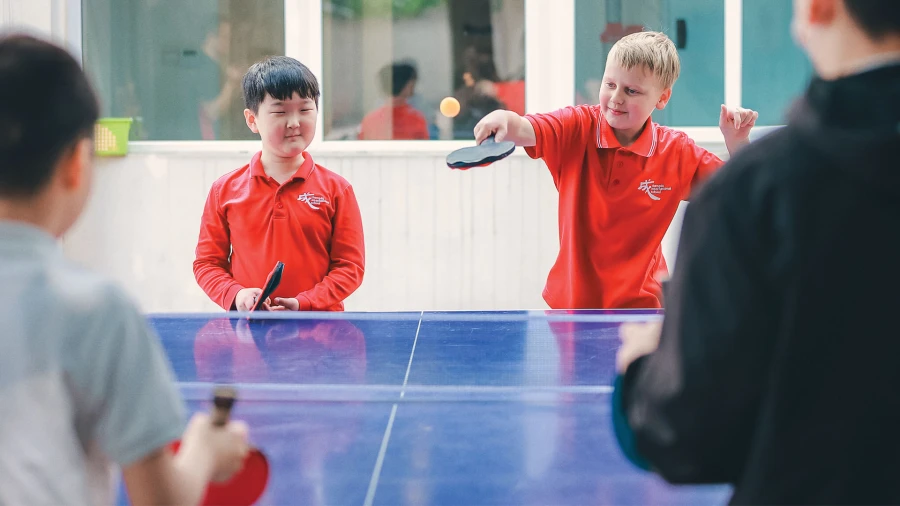 young male students playing ping pong at chengdu international school elementary gym class