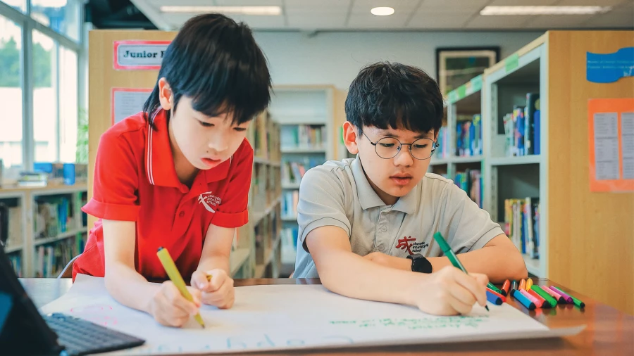 two young male students inside the library at chengdu international school learning to work together
