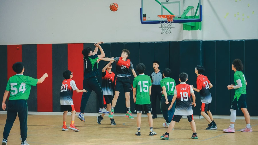 boys playing basketball inside the gym at chengdu international school